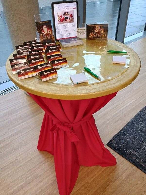 Stehtisch mit roter Husse und goldener Tischplatte, darauf Visitenkarten, Tablet und QR-Code-Aufsteller
